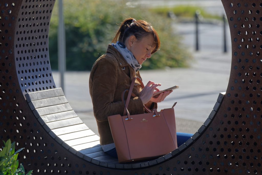 A woman in a park browsing a website on her mobile device.